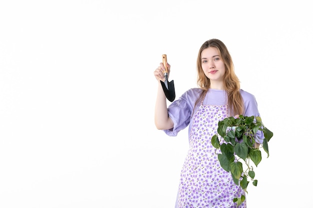 widok z przodu młoda kobieta trzyma szpatułkę i kwiat na białym tle kwiat trawa zakupy ogród gleba ziemia roślina kobieta