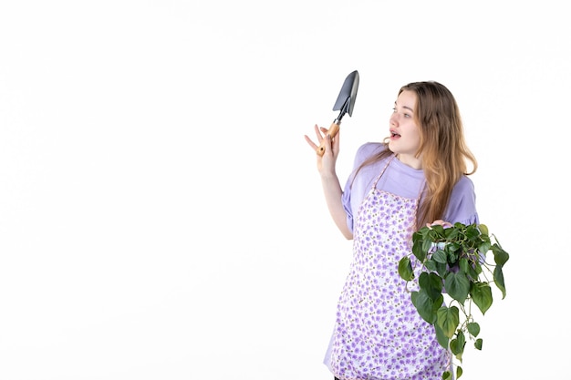 widok z przodu młoda kobieta trzyma szpatułkę i kwiat na białym tle kwiat trawa zakupy ogród gleba ziemia roślina
