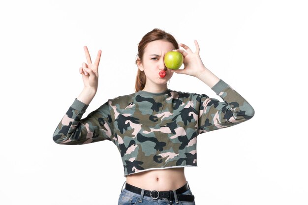 Widok z przodu młoda kobieta trzyma zielone jabłko białe tło pozioma dieta posiłek kolory ludzkie danie jedzenie sok owocowy