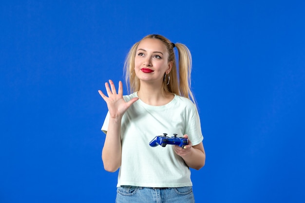 Zdjęcie widok z przodu młoda kobieta z gamepadem na niebieskim tle dorosła sofa wideo online wygrywająca młodzież wirtualny radosny internet