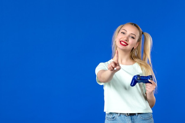 widok z przodu młoda kobieta z gamepadem na niebieskim tle młodzież online dla dorosłych internet wygrywająca wirtualna radosna sofa z odtwarzaczem wideo