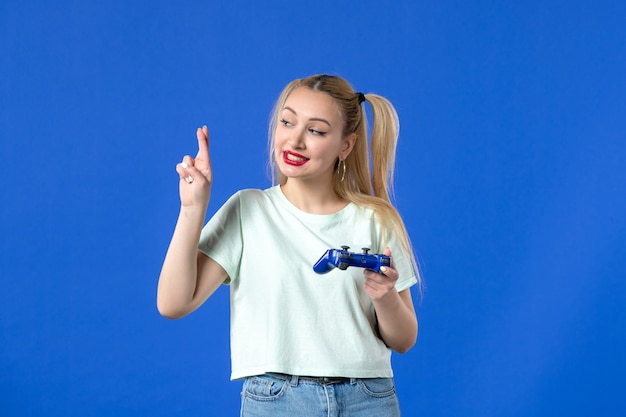 widok z przodu młoda kobieta z gamepadem na niebieskim tle wirtualne wideo wygrywające online radosny joystick młodzieżowy dorosły gracz