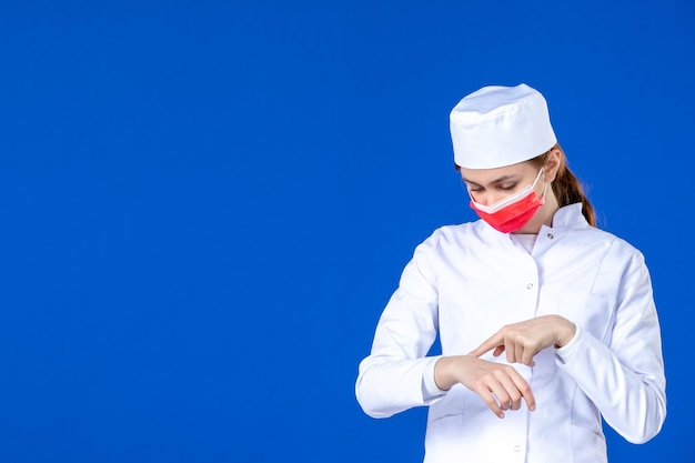 Widok z przodu młodej pielęgniarki w garniturze z czerwoną maską na niebiesko