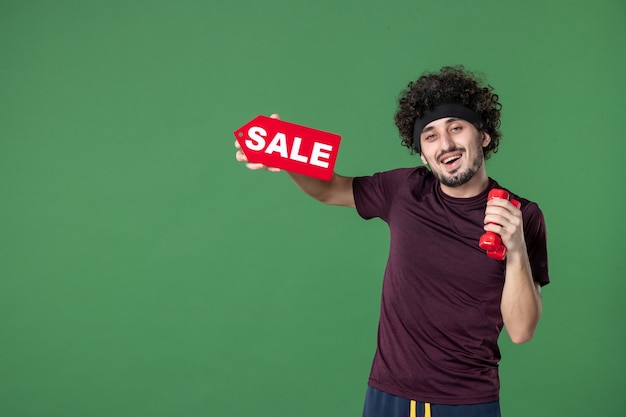 widok z przodu młody mężczyzna trzymający hantle i sprzedaż pisanie na zielonym tle sport siłownia trening model zdrowie zakupy kolor