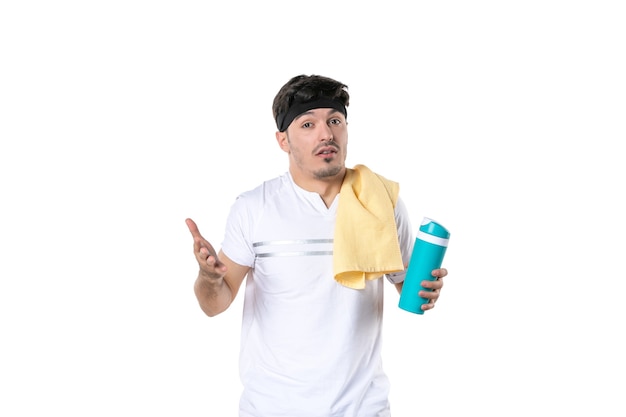 widok z przodu młody mężczyzna trzymający termos po sesji treningowej na białym tle sportowiec sport styl życia ciało dieta joga siłownia zdrowie fit