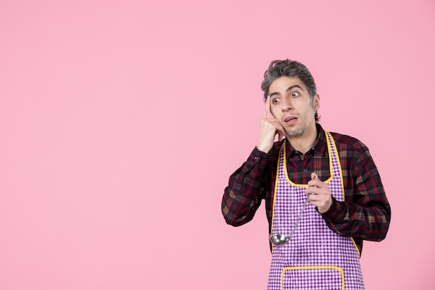 widok z przodu młody mężczyzna w pelerynie trzymający łyżkę do zupy na różowym tle praca zawód pracownik poziomy jedzenie mąż kuchnia kucharz kolor