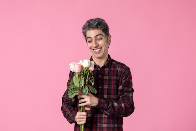 Widok z przodu młody mężczyzna z pięknymi różowymi różami na różowej ścianie