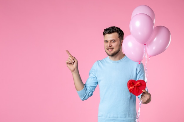 widok z przodu młody mężczyzna z uroczymi różowymi balonami i prezentem w kształcie serca na różowym tle miłość zmysłowa równość dzień kobiet małżeństwo marzec kobiecy park data zabawa