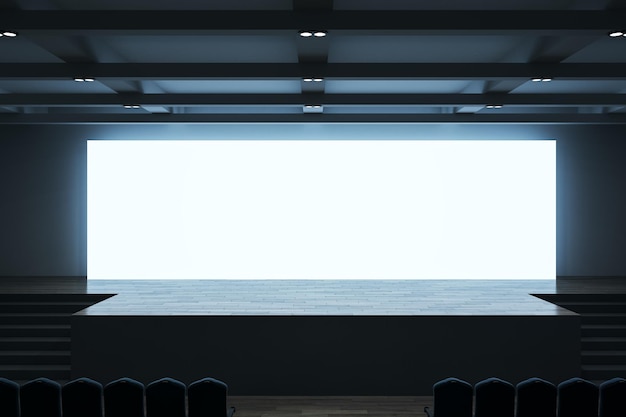 Widok z przodu na duży pusty biały podświetlany ekran z miejscem na tekst lub logo i niebieskim podświetleniem w pustej ogromnej sali ze schodami sceny i rzędami siedzeń Makieta renderowania 3D