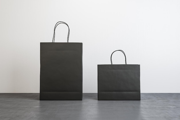 Widok z przodu na dwie czarne puste papierowe torby na zakupy z miejscem na logo lub tekst na betonowej podłodze na białym tle Makieta renderowania 3D