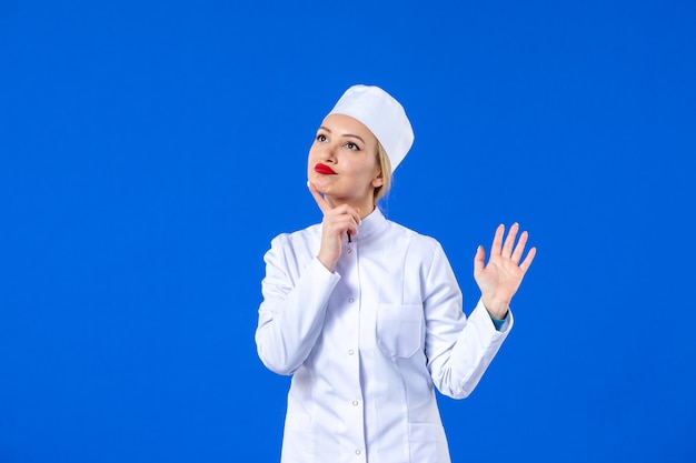 widok z przodu na myślenie młoda pielęgniarka w białym garniturze medycznym na niebieskim tle medycyna choroba pandemiczna szpital covid- wirus choroba zdrowie lek