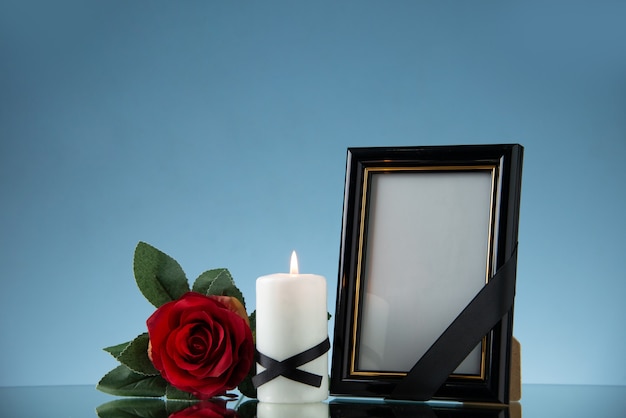 Widok z przodu ramki na zdjęcia ze świecą i czerwonym kwiatem na niebieskiej powierzchni śmierci zły pogrzeb