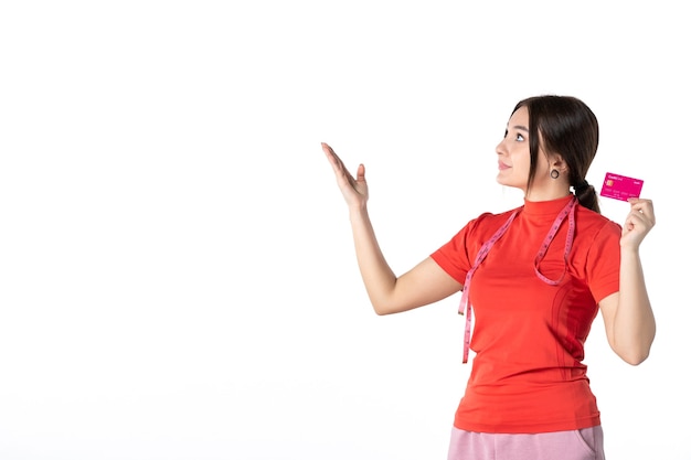 Widok z przodu skupionej pięknej dziewczyny w czerwonopomarańczowej bluzce pokazującej kartę bankową skierowaną w górę na białym tle