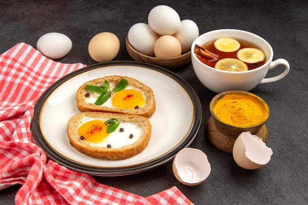 widok z przodu smaczne grzanki jajeczne z herbatą na ciemnym tle posiłek chleb omlet jedzenie obiad rano śniadanie herbata