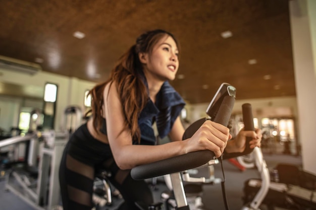 Widok z przodu treningu kobiety z rowerem. Kobiety ćwiczą w siłowni dla zdrowego stylu życia na rowerze o zachodzie słońca. fitness, trening, ćwiczenia na siłowni, styl życia i zdrowa koncepcja.