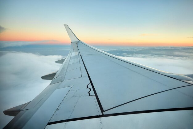 Zdjęcie widok z skrzydła samolotu samolotu pasażerskiego o zachodzie słońca z chmurnym niebem podróżując w czasach covid