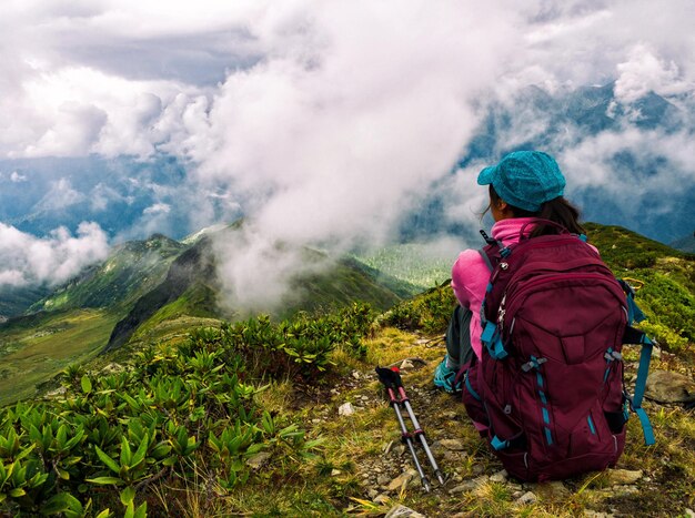 Widok Z Tyłu Aktywnej Kobiety Z Kijkami Trekingowymi Patrzącej Na Góry W Chmurach