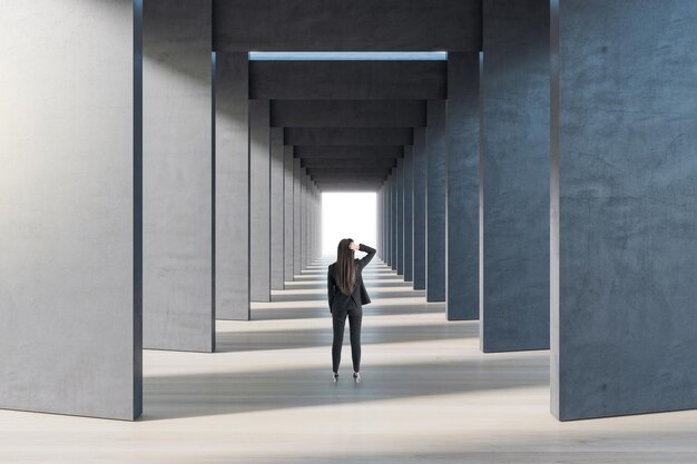 Widok z tyłu bizneswoman w abstrakcyjnym betonowym kwadratowym korytarzu Koncepcja przestrzeni i korytarza