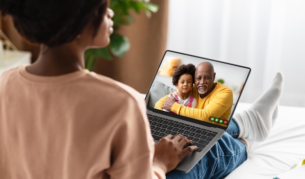 Widok z tyłu czarnej kobiety dzwoniącej do swojej rodziny za pomocą komputera