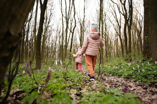 Widok z tyłu dwóch sióstr chodzących leśnym szlakiem Koncepcja wypoczynku wiosennego na świeżym powietrzu