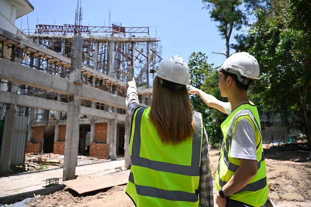 Widok z tyłu inżynier budowlany omawiający wspólnie szczegóły planowania rozwoju na placu budowy