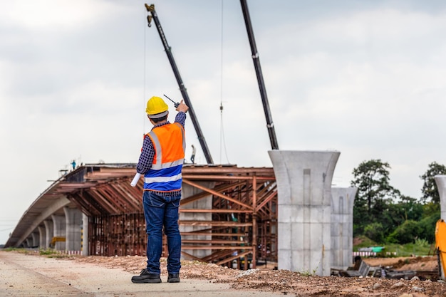 Widok z tyłu inżyniera podczas inspekcji i sprawdzania projektu na budowie Brygadzista w kasku na budowie infrastruktury