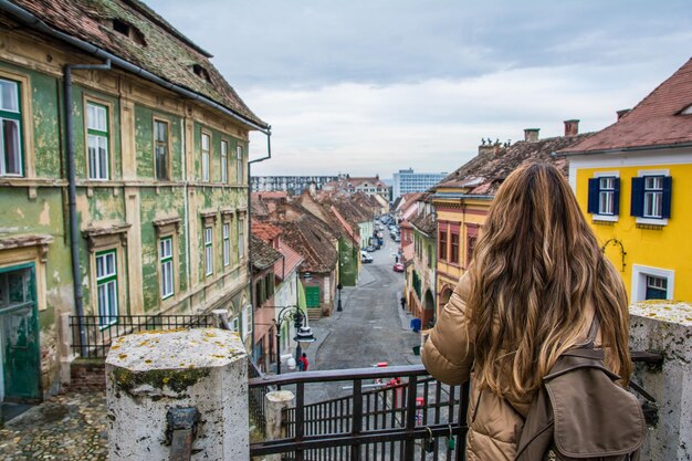Widok Z Tyłu Kobiety Patrząc Na Kolorowe Ulice Sibiu, Romania.Travels I Turystyka