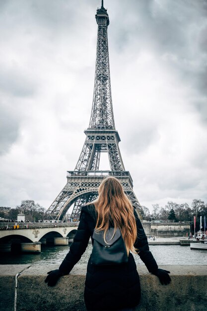 Widok z tyłu kobiety stojącej przy wieży Eiffla