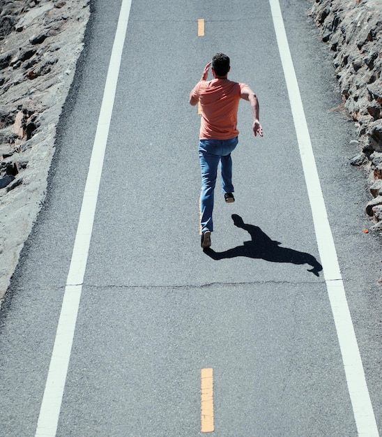 Widok z tyłu mężczyzny biegnącego na drodze wysportowany młody mężczyzna biegający na zewnątrz