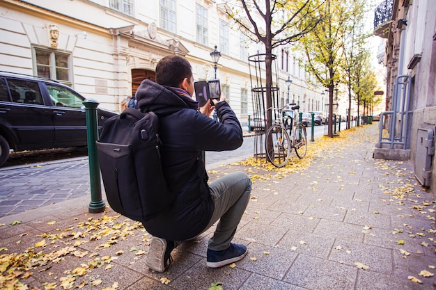 Widok z tyłu mężczyzny fotografującego ulicę europejskiego miasta Turysta robi zdjęcie smartfonem w jesienny dzień
