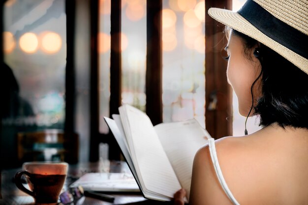 Widok Z Tyłu Młoda Kobieta Czytając Książkę Siedząc W Kawiarni.