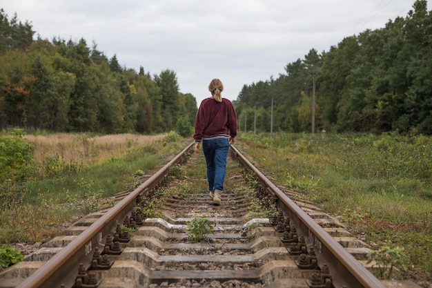 Widok z tyłu młodej kobiety odchodzącej wzdłuż torów kolejowych Koncepcja odjazdu