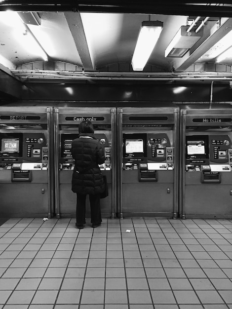 Zdjęcie widok z tyłu osoby stojącej przed automatycznym bankomatem na lotnisku