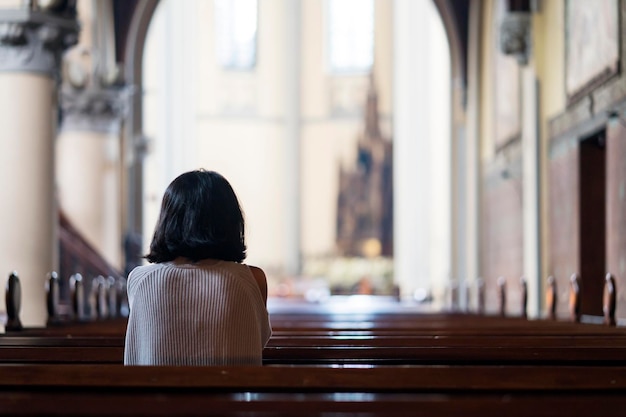 Widok z tyłu pobożnej kobiety modlącej się w kościele