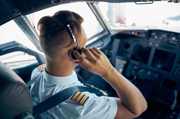 Widok Z Tyłu Portret Pewny Siebie Pilota W Mundurze Ze Słuchawkami Podczas Pracy W Kabinie