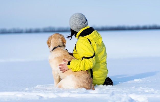 Widok Z Tyłu Przyjaznego Psa I Kobiety Siedzącej Na śnieżnym Polu