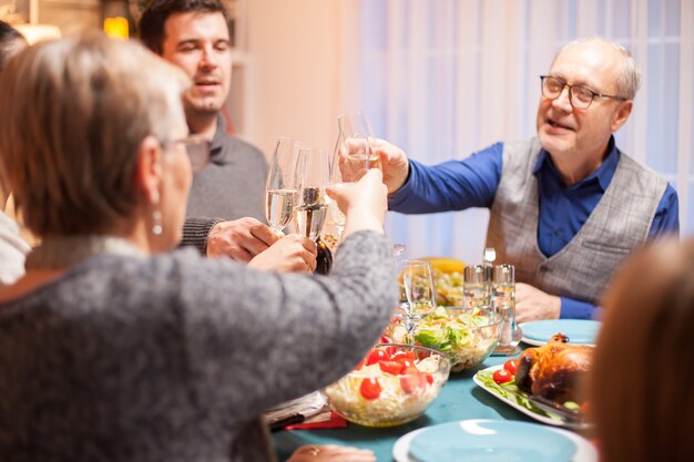 Widok Z Tyłu Starszej Kobiety Brzęk Kieliszek Wina Z Rodziną Podczas świątecznej Kolacji.