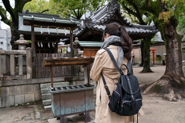 widok z tyłu turystki doświadczającej japońskiej kultury i błogosławieństwa w świątyni