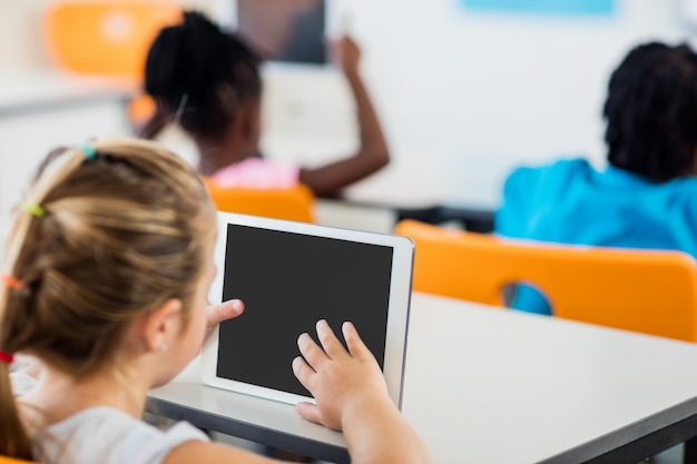 Widok z tyłu ucznia za pomocą komputera typu tablet w klasie