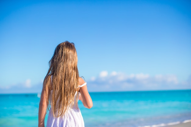 Widok z tyłu urocza dziewczynka na białej plaży podczas letnich wakacji