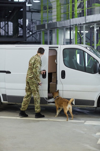 Widok z tyłu wojskowego z psem sprawdzającym ładunek w ciężarówce przed dostawą