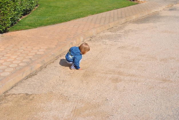 Zdjęcie widok z wysokiego kąta chłopca przykucanego na chodniku