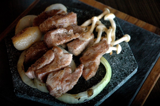 Zdjęcie widok z wysokiego kąta grillowanej cebuli mięsnej i grzybów na talerzu na stole