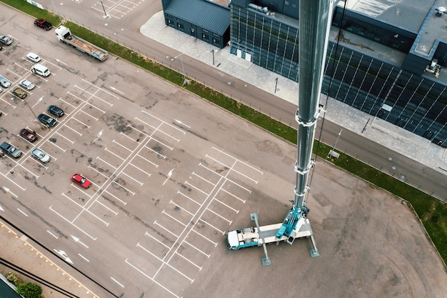 Widok z wysokości dźwigu samochodowego, który stoi otwarty na parkingu i gotowy do pracy. najwyższy dźwig samochodowy jest rozstawiony na miejscu. wysokość wysięgnika to 80 metrów