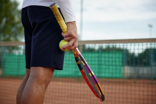 Widok zbliżenie na rakietę tenisową i piłkę w ręku na sportowca na tle boiska sportowego na świeżym powietrzu. Profesjonalne wyzwanie konkursowe lub trening w klubie fitness