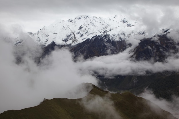 Widoki na ośnieżone szczyty górskie w chmurach w lantang