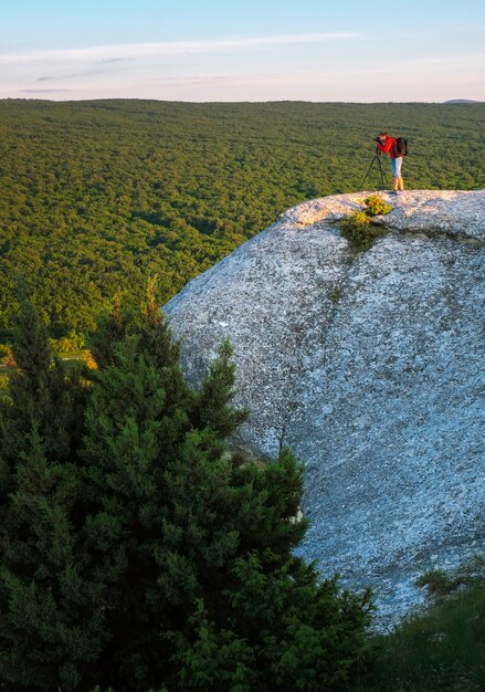 Wieczorem fotograf robi zdjęcia scenerii na skale.