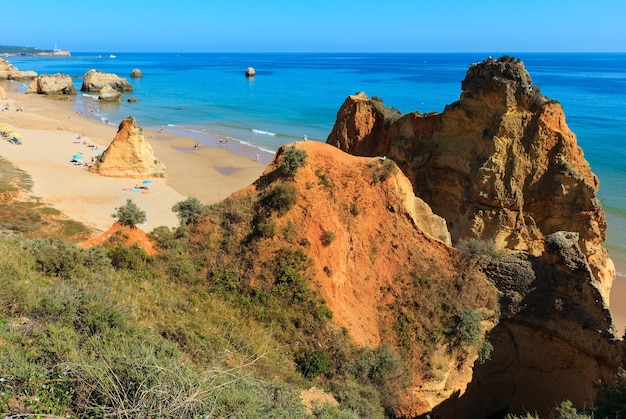 Wieczorem piaszczysta plaża Praia dos Tres Castelos z formacjami skalnymi, Portimao, Algarve, Portugalia. Widok z góry. Ludy są nie do poznania.