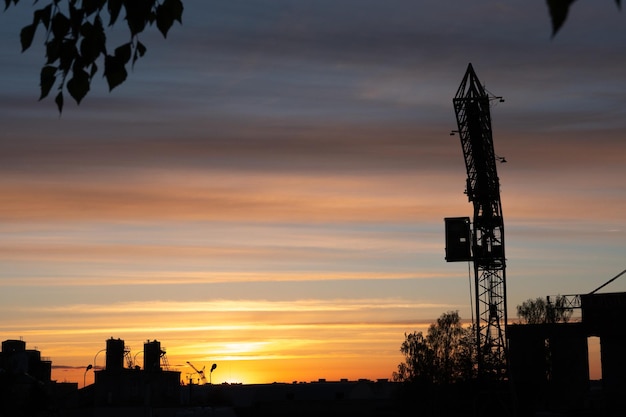 Wieczorny zarys miasta Sylwetka fabryki na tle nieba lub zachodu słońca Żuraw wieżowy działa na terenie fabryki