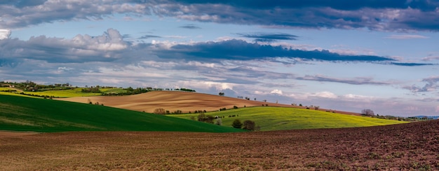 Zdjęcie wiejski krajobraz z falami pól i błękitnym niebem z chmurami wiosna sezonowe naturalne tło